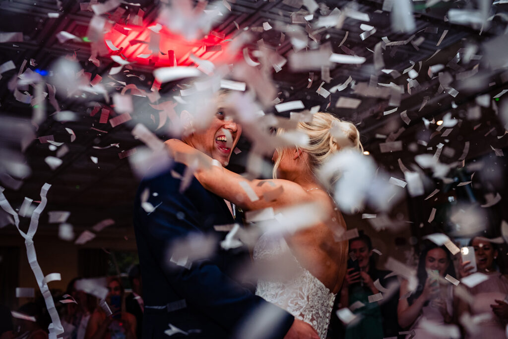 A happy couple celebrating their marriage. Their guest are setting off confetti cannons.