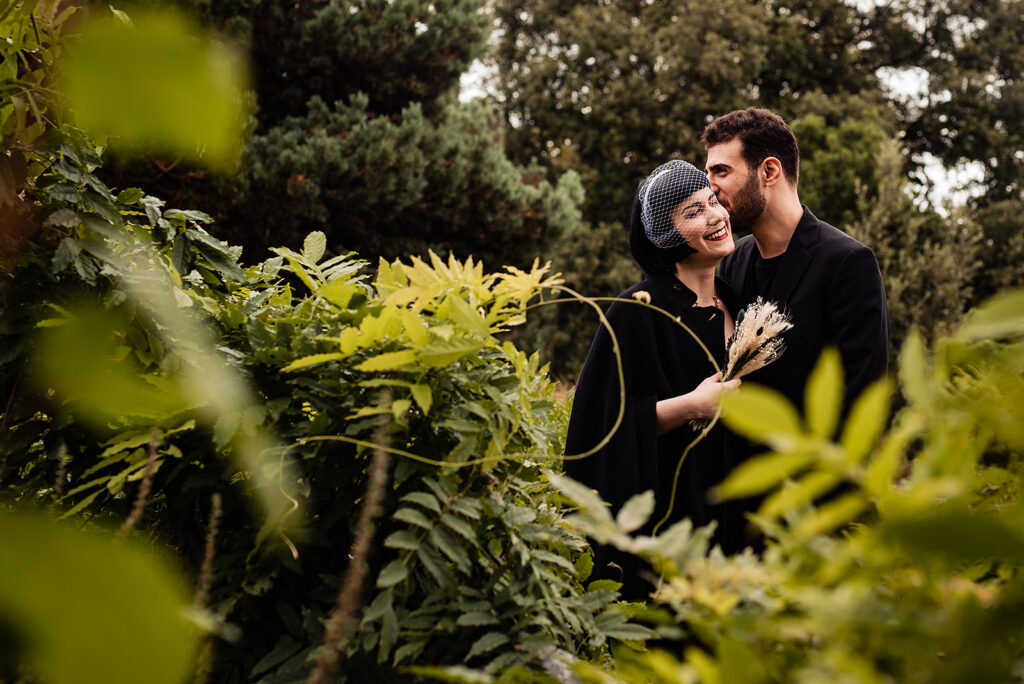 A bride and groom have some photos together in Regent's Park, London, they stand amongst the greenery. 