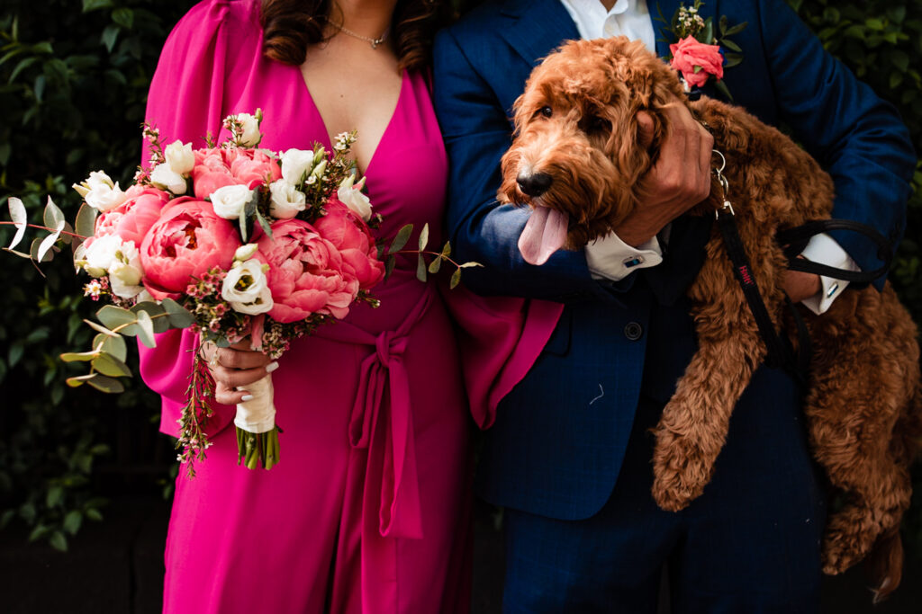 A bride and groom hold their dog at their wedding day