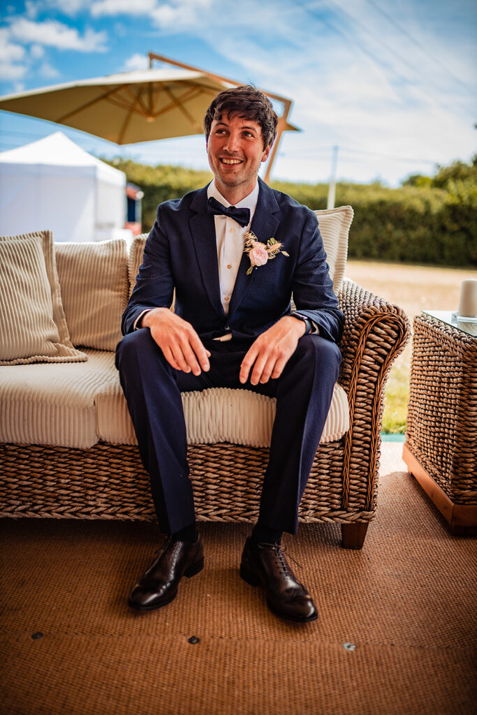 The groom smiles as he wears a Paul Smith suit with a bow tie at his wedding. 