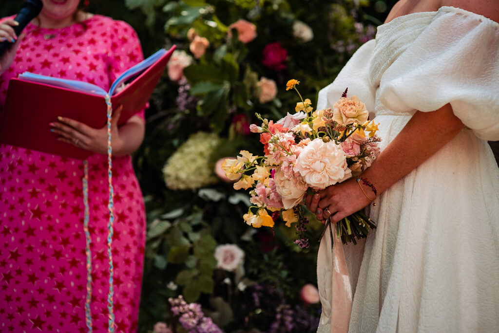 A bride holds her summer bouquet against a backdrop of statement installation flowers
