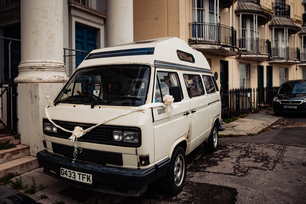 An Alternative wedding: The wedding transport is an old cream camper van, decorated with ribbons. 