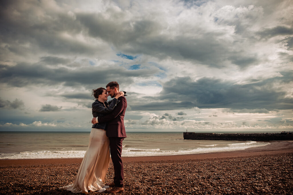 An Alternative wedding: A couple (bride and groom) stands on the beach during their photo shoot on their wedding day