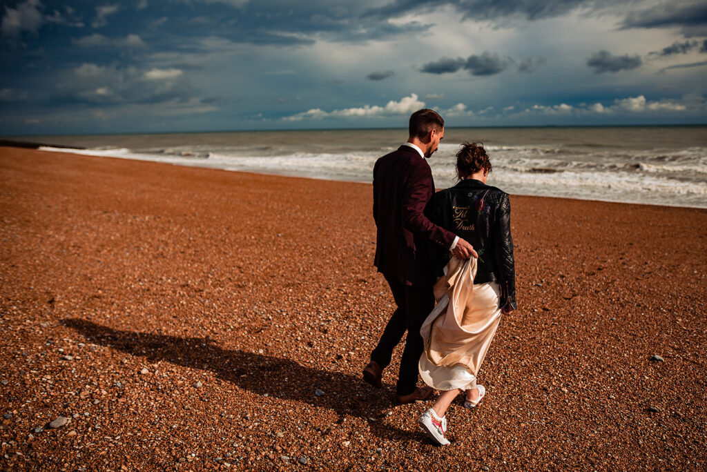 An Alternative wedding: A couple (bride and groom) walk on the beach during their photo shoot on their wedding day