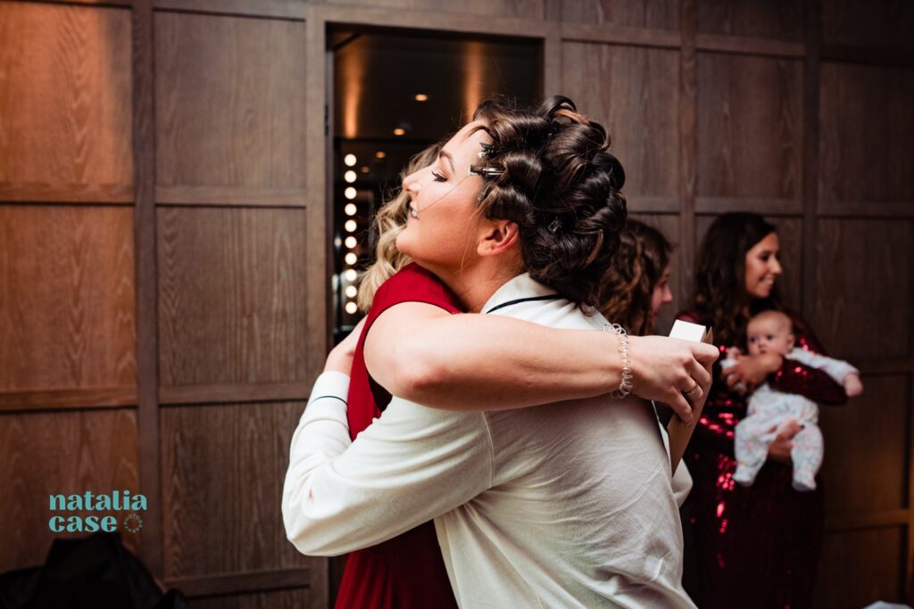 A bride hugs one of her bridesmaids in the Londoner Hotel, on the morning of her London winter wedding.