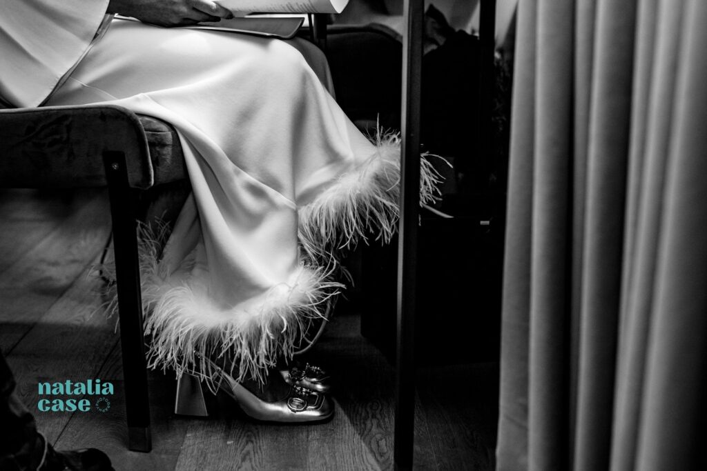 A close up of shoes and a fringed wedding dress. 