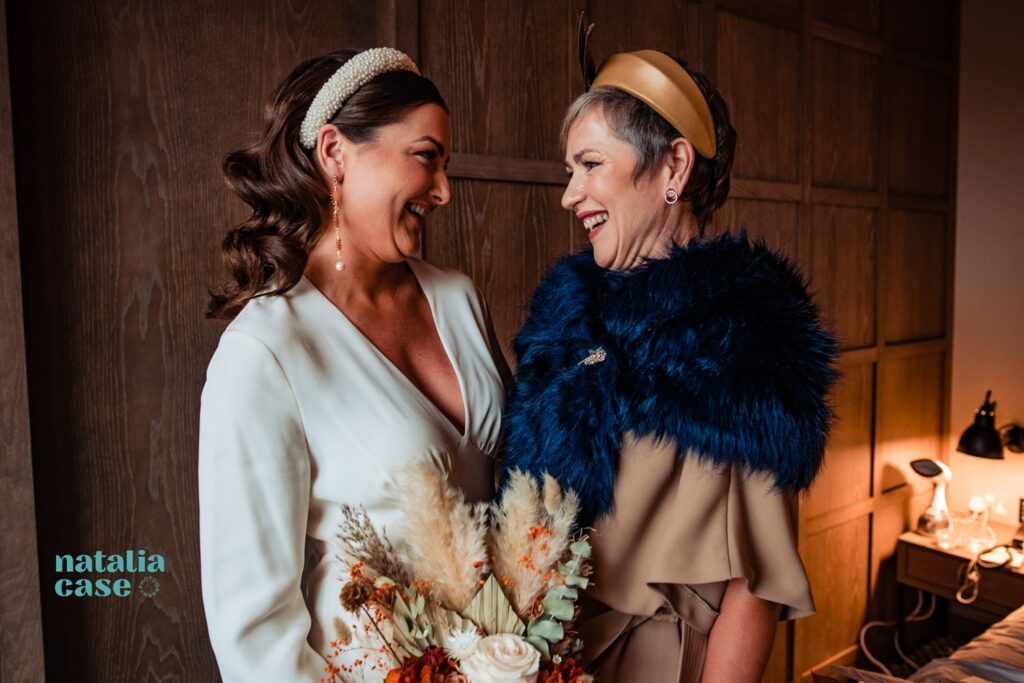 A bride and her mother smile at each other on the morning of her wedding, getting ready at The Londoner. 