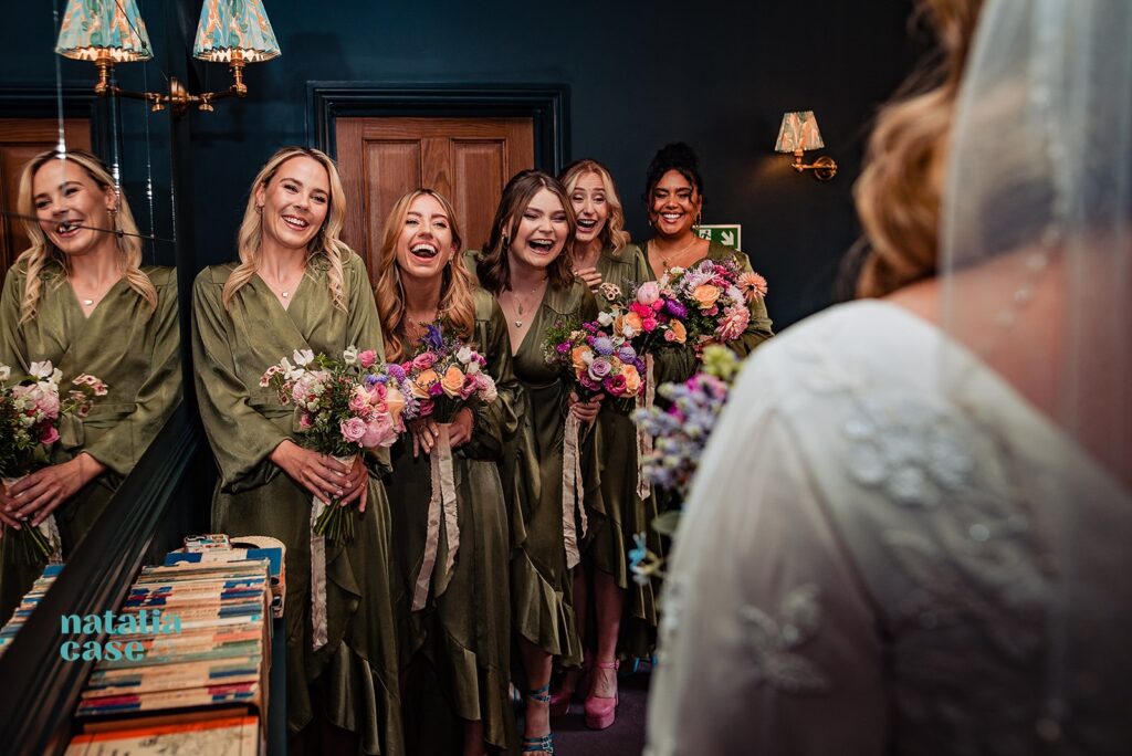 The bridesmaids react to seeing the bride in her wedding dress on the morning of a wedding