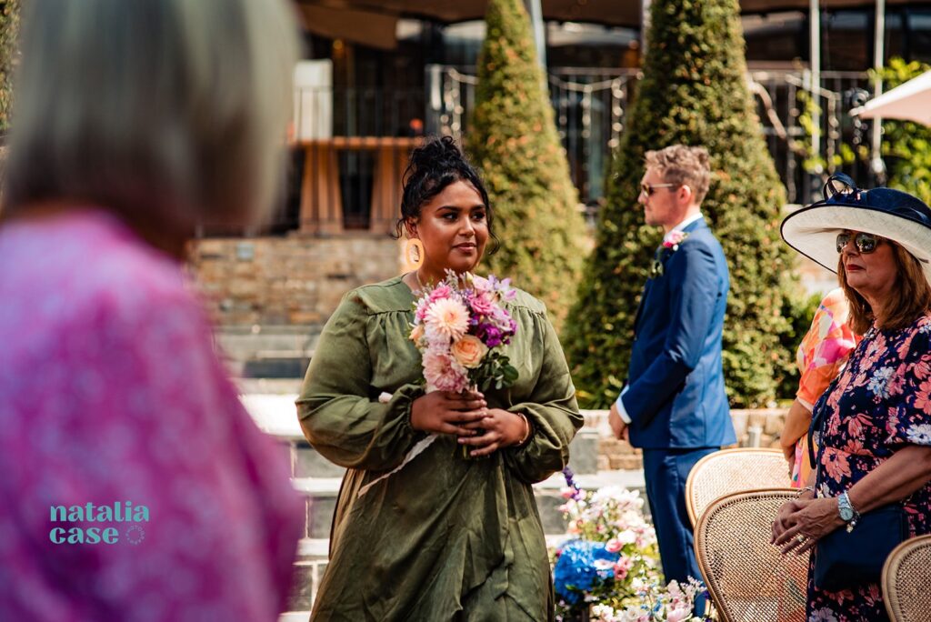 A bridesmaid walks down the aisle at an outdoor wedding ceremony at The Bingham Riverhouse, Richmond