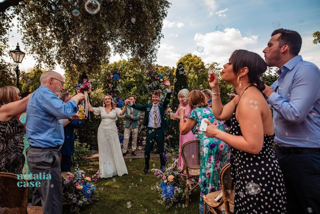 Guests blow party bubbles as the bride and groom walk back down the aisle. 