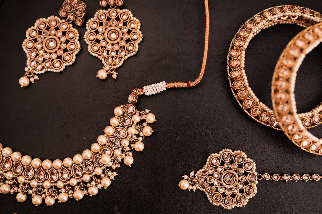 Traditional Indian Hindu jewellery. The gold of the jewellery stands out against the dark background. It's in a flatlay birds eye angle.