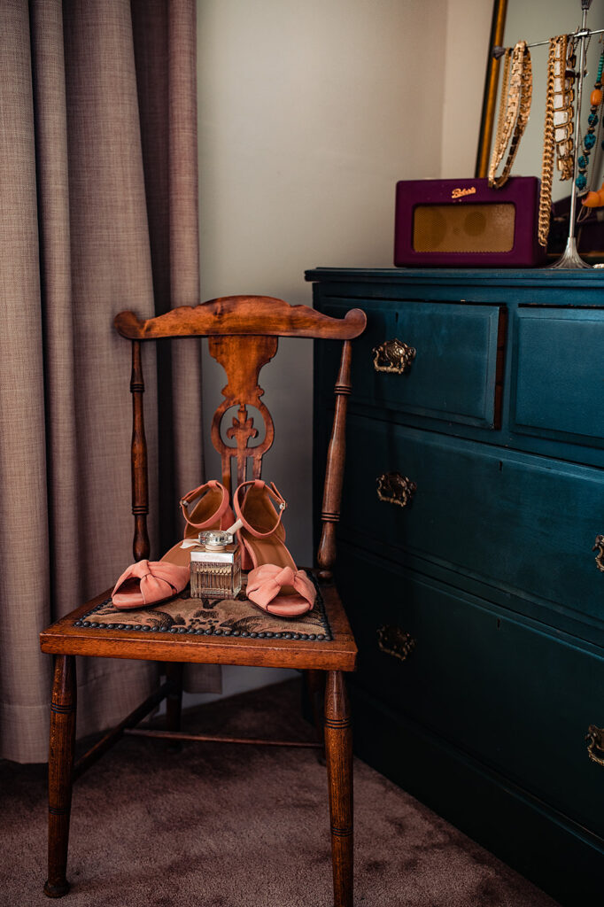 The bride's pastel pink shoes are set on an antique wooden chair, along with her Chloé perfume. 